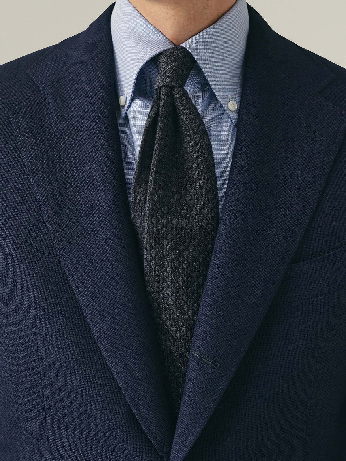 Person wearing navy blazer with blue shirt and dark grey tie
