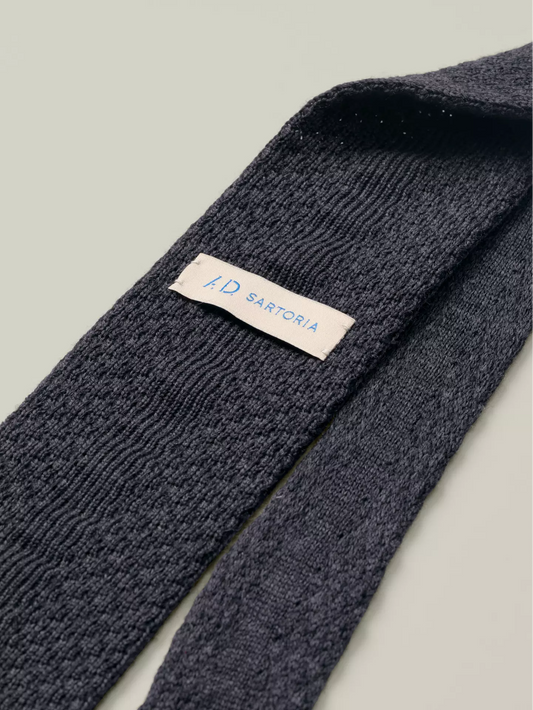 Dark grey knitted tie with a visible brand label