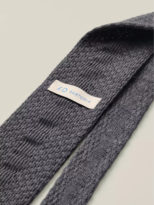 Grey knitted tie with a visible brand label