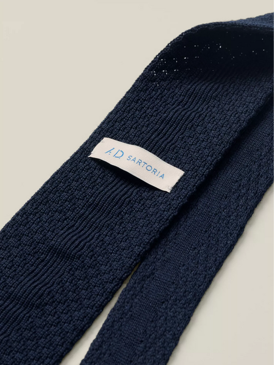 Navy blue knitted tie with a visible brand label
