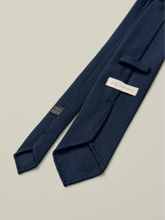 Navy blue knitted tie with a brand label