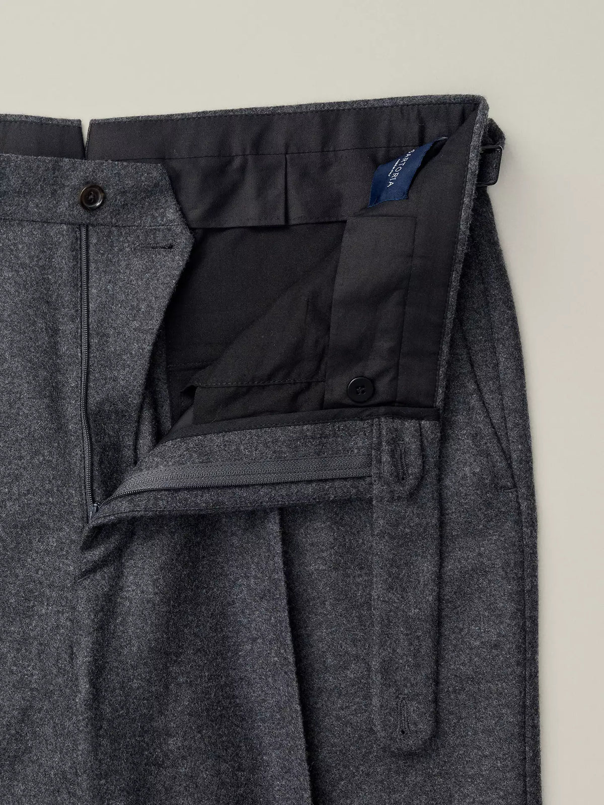 Gray flannel pants with a close-up of the pocket and brand label