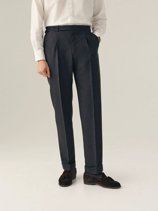 Person wearing dark grey pleated trousers with a white shirt