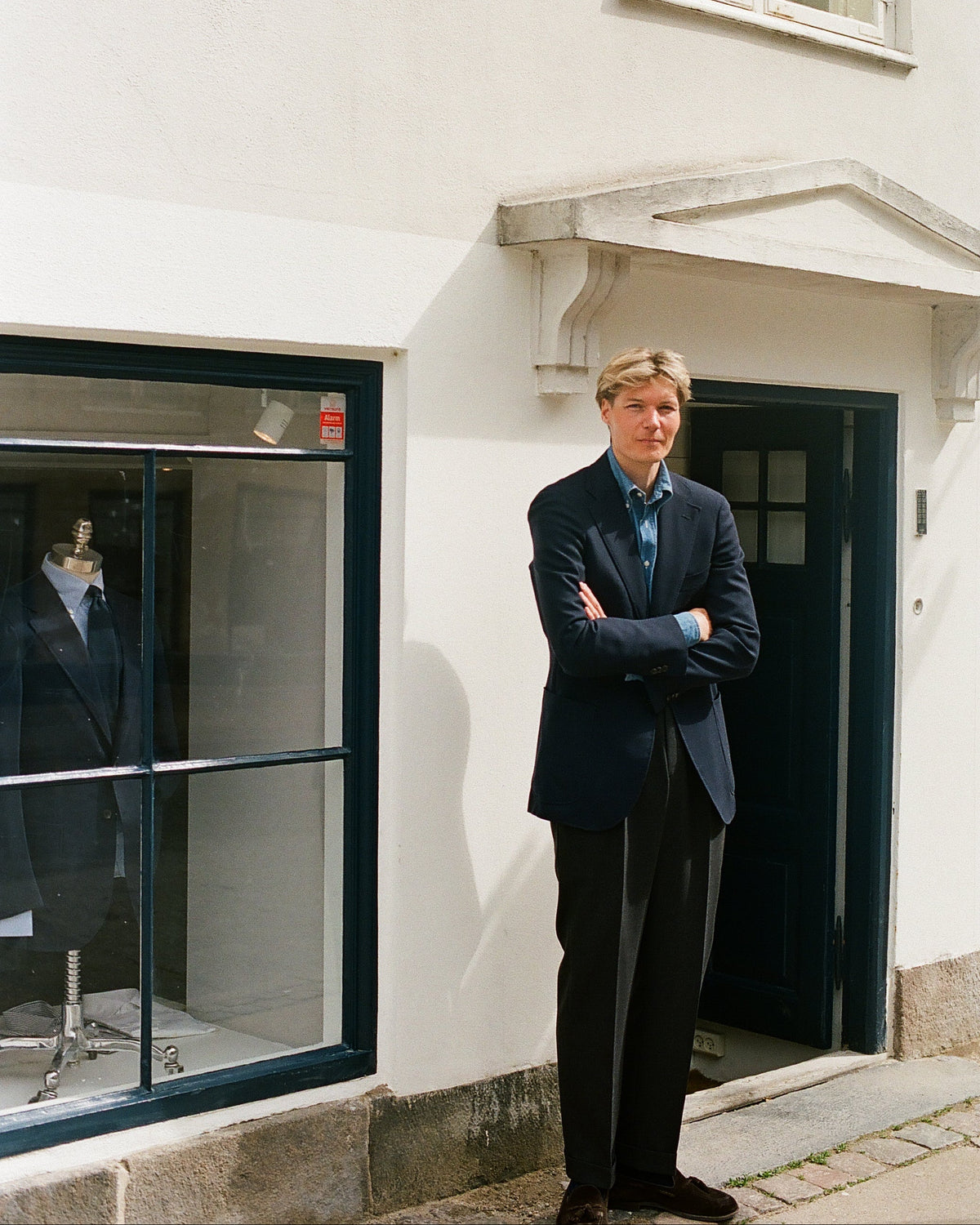 Man in a suit standing outside a building with a window display.