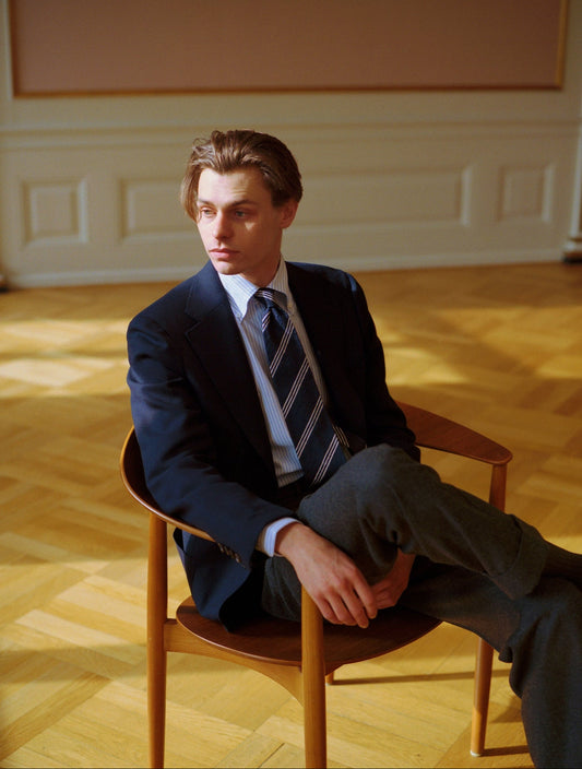 Man in a suit sitting on a wooden chair in navy blazer  - A. D. Sartoria