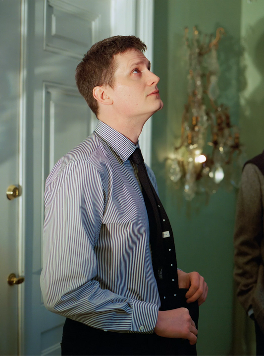 Man adjusting his tie in a room with a chandelier