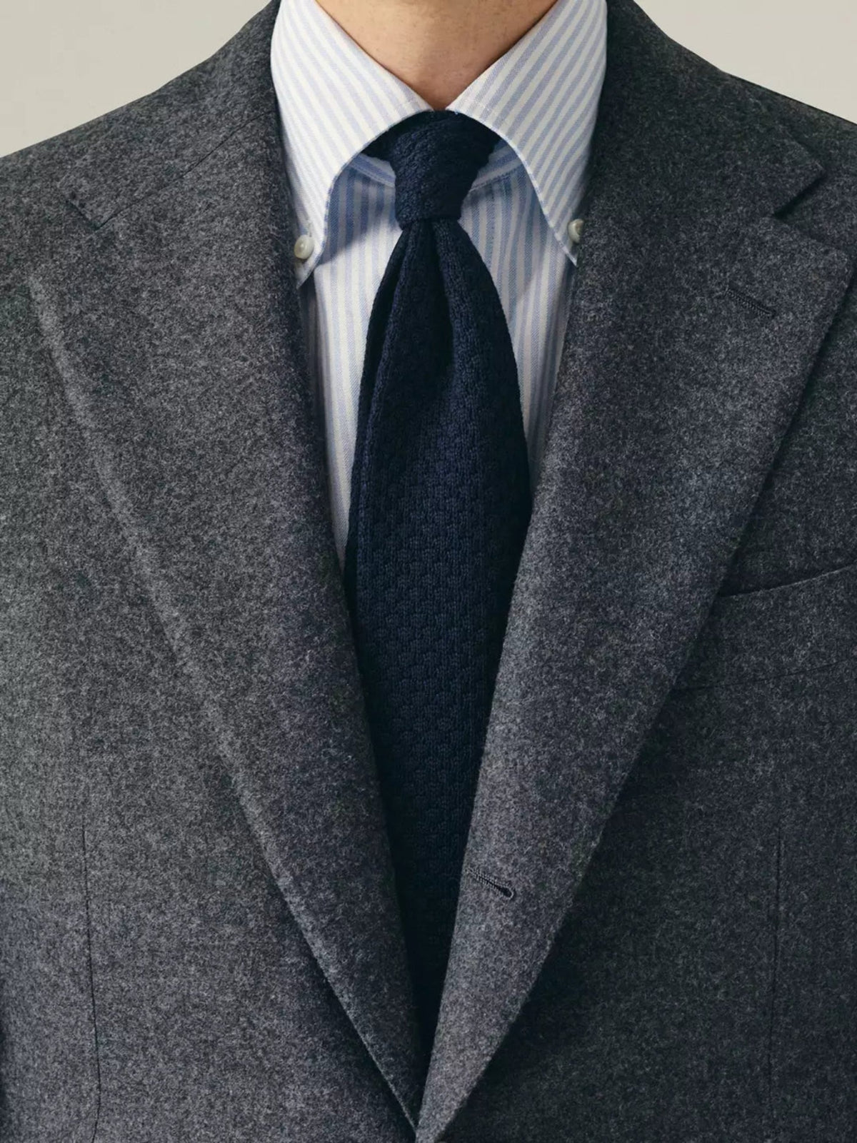 Gray suit jacket with a navy tie and striped shirt