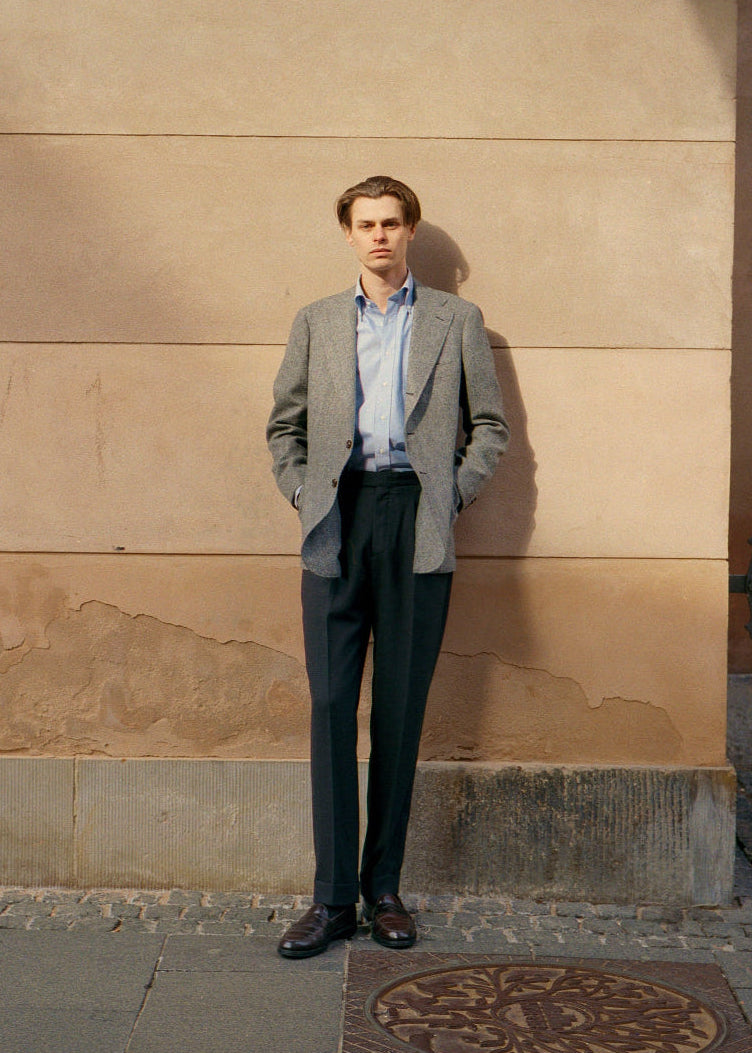 Man in a suit standing against a beige wall