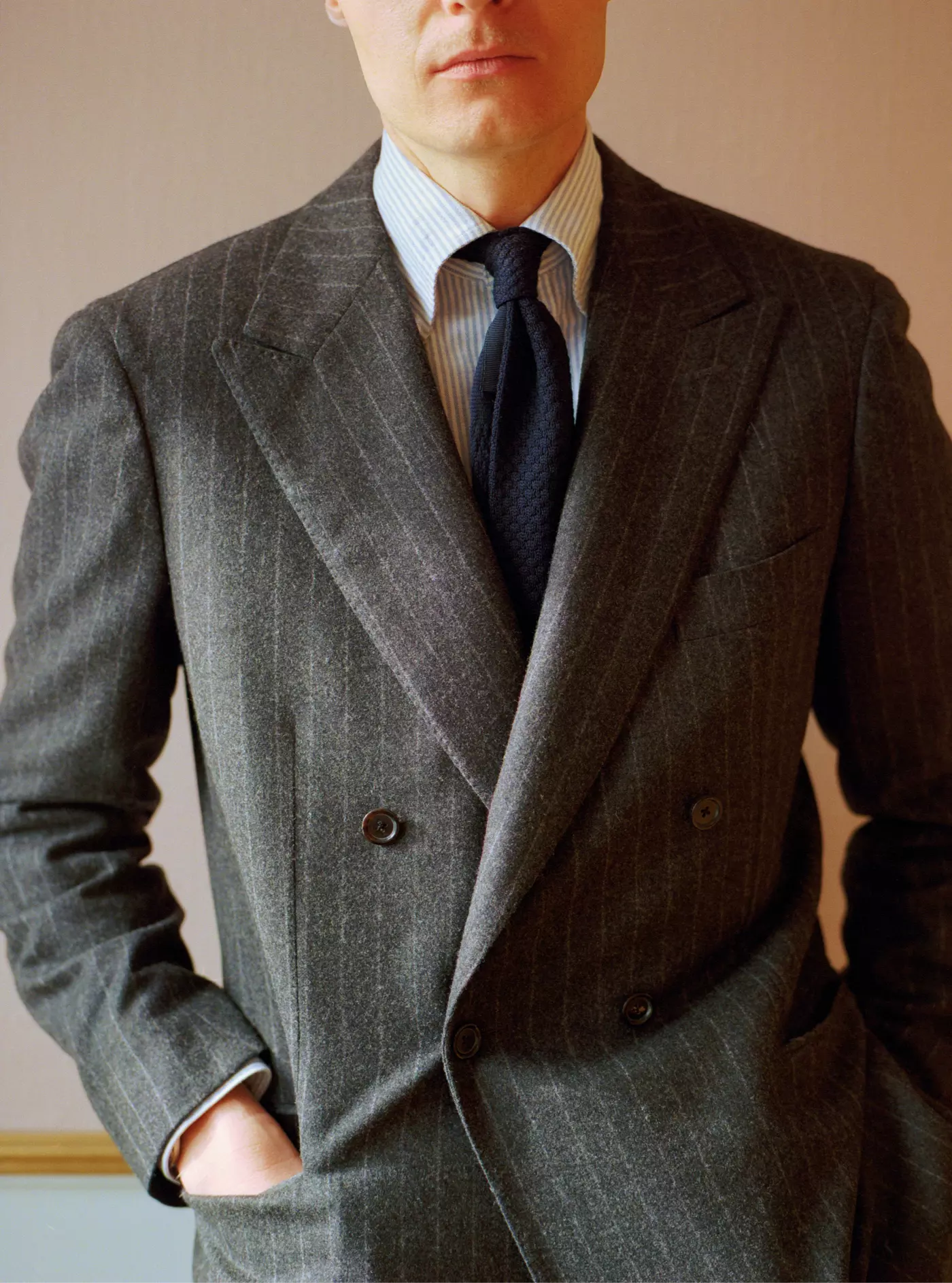 Man wearing a gray double-breasted suit with a plain background