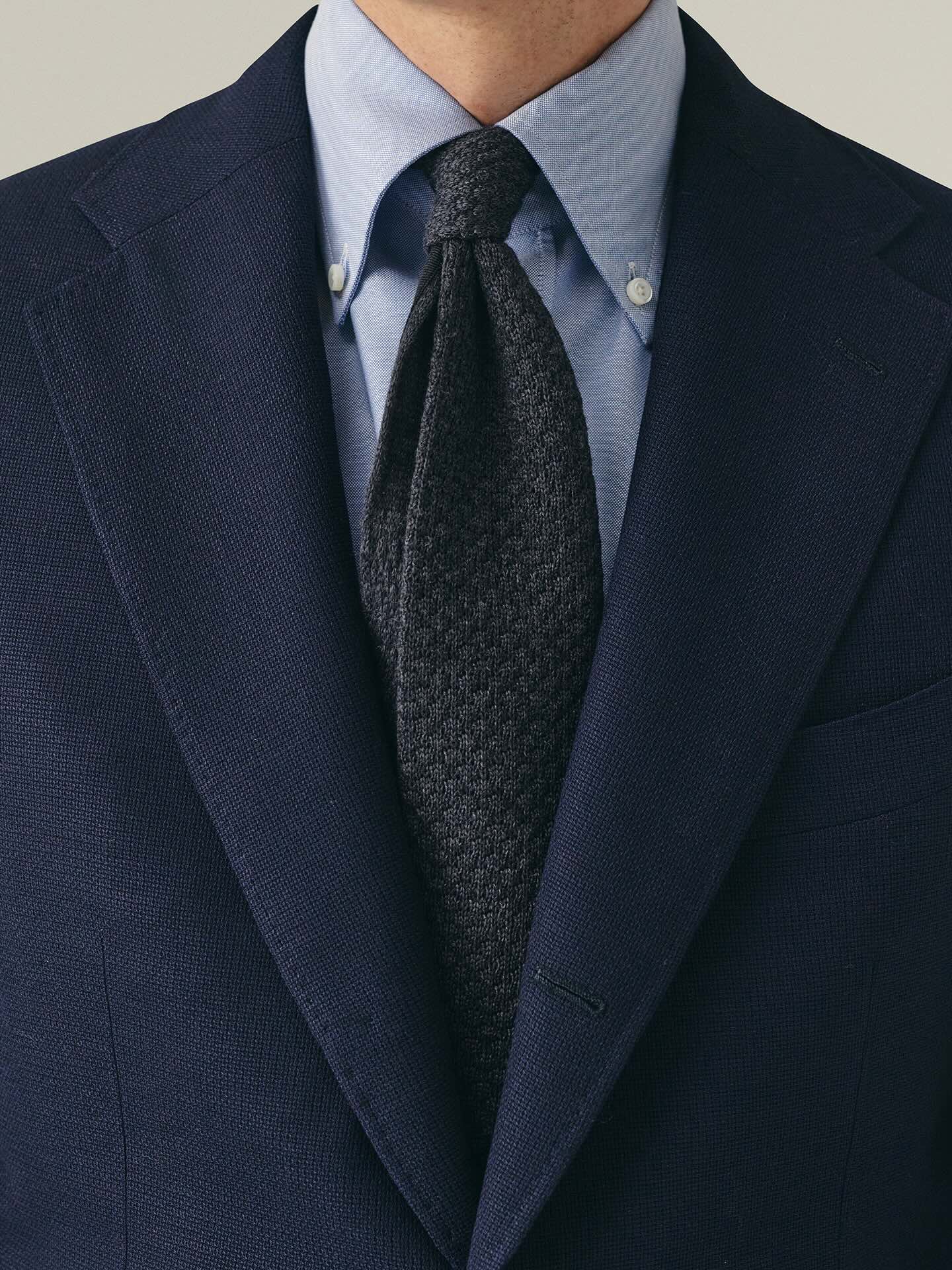 Person wearing navy blazer with blue shirt and dark grey tie