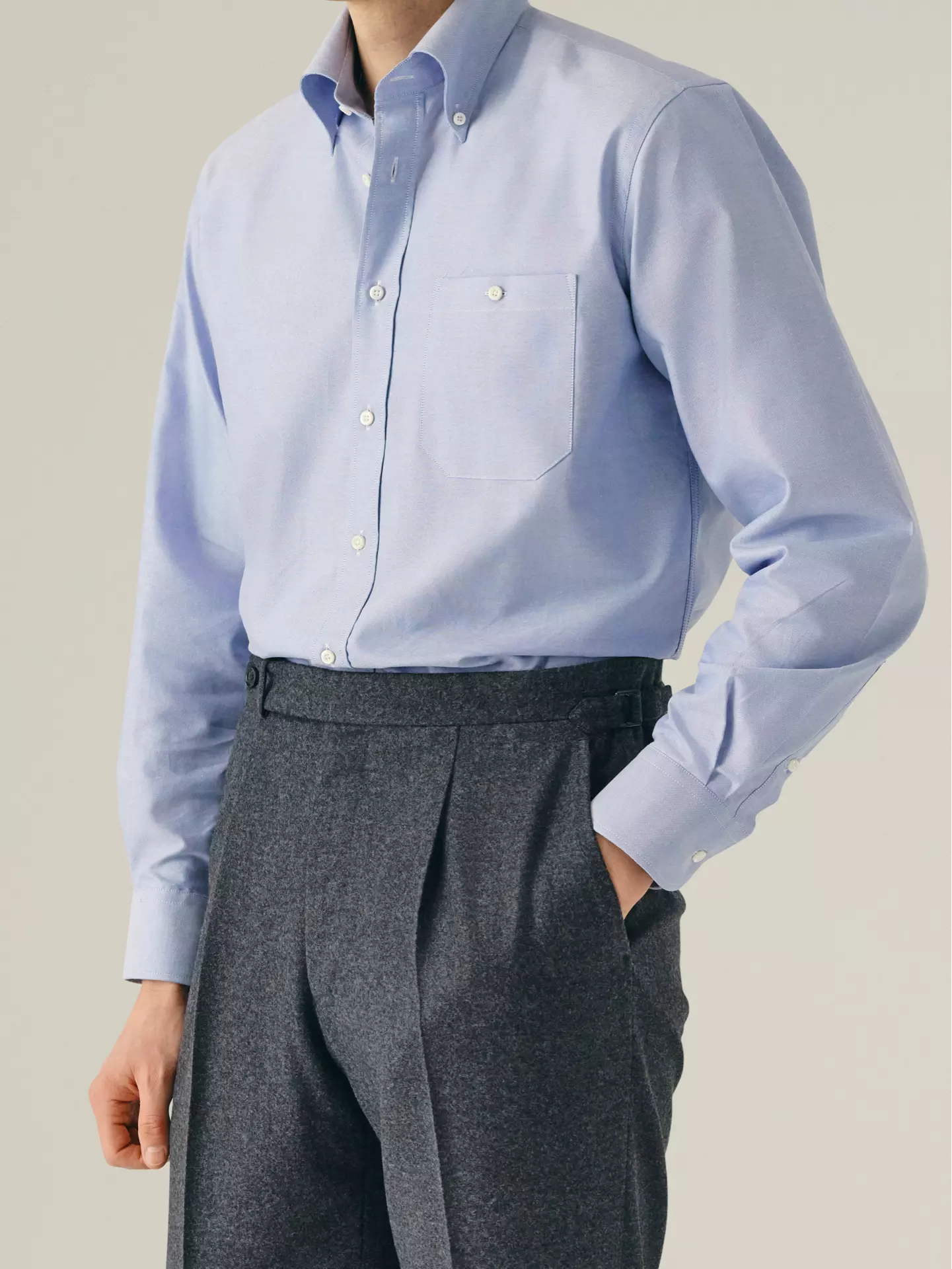Person wearing a light blue button-down shirt and gray pleated pants