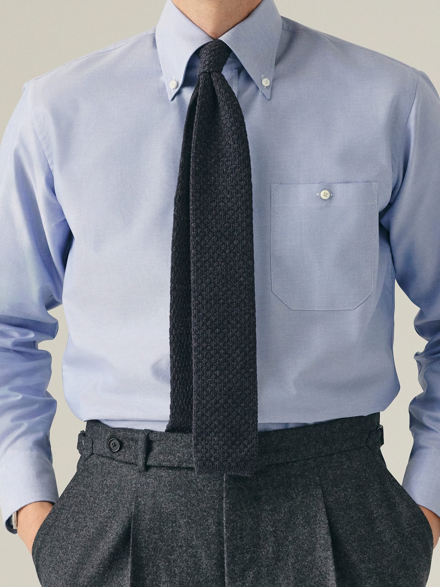 Person wearing blue OCBD shirt with dark grey knitted tie