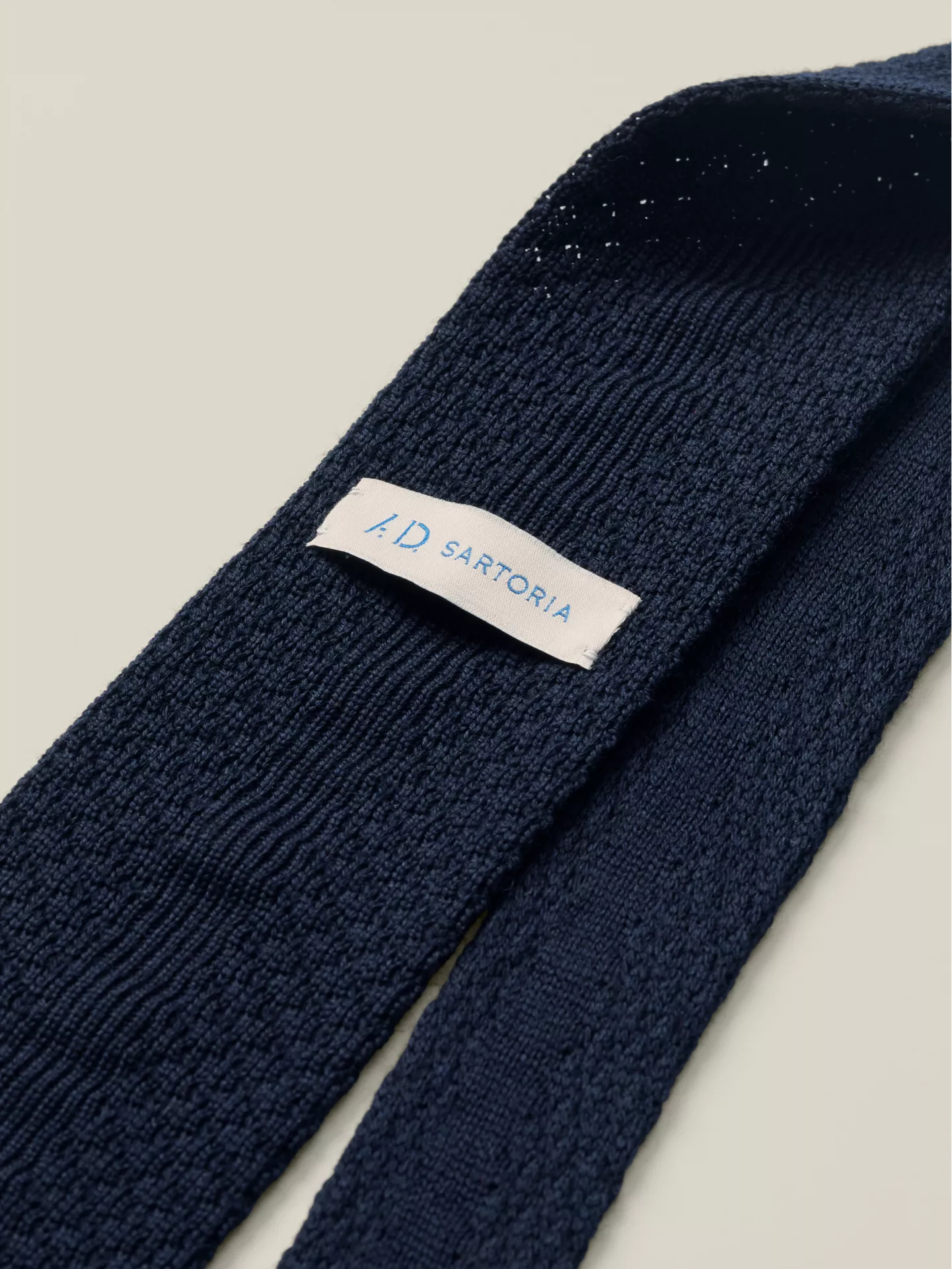 Navy blue knitted tie with a visible brand label 