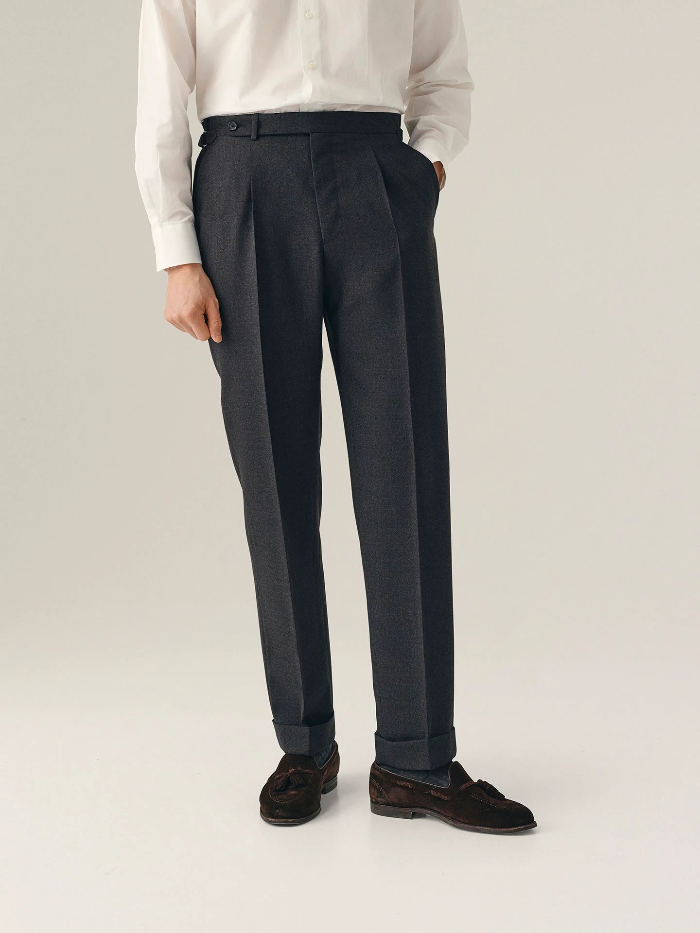 Person wearing dark grey pleated trousers with a white shirt